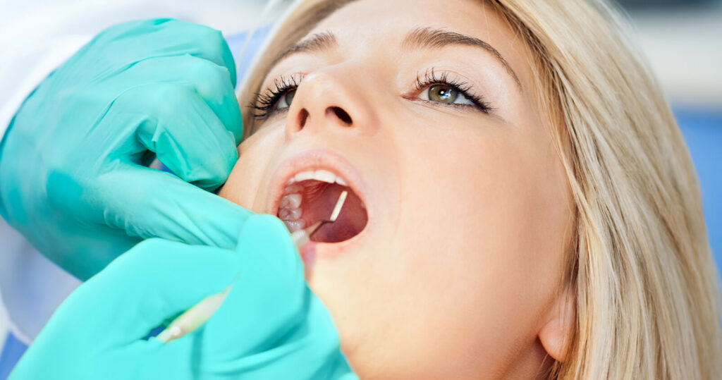 A dentist looking in a young woman's mouth.
